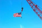 crane-holding-american-flag-against-blue-sky-55191195.jpg